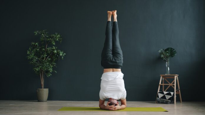 Photo by Vitaly Gariev Woman performing a headstand yoga pose indoors.