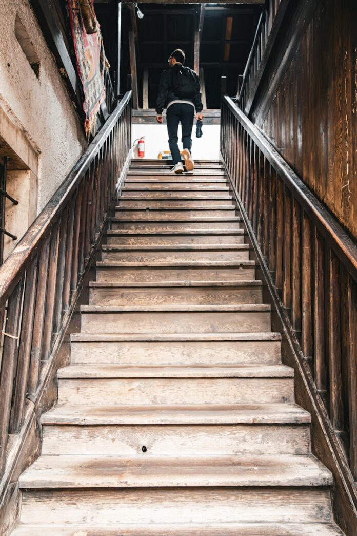 Photo by Furkan Durmuş A person walks up a wooden staircase.